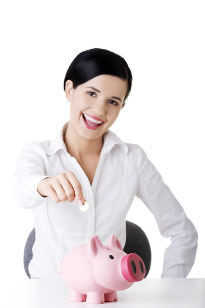 Businesswoman putting a coin into a piggy bank - Фото, зображення