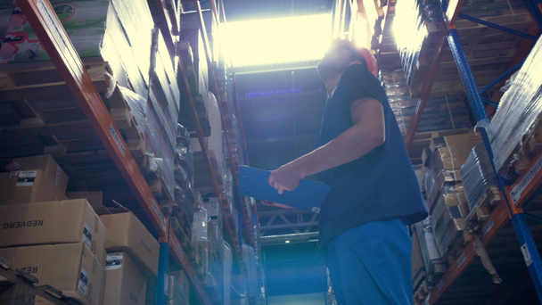 Pracovník skladu vyhledá na vysoký strop skladovací regály. - Záběry, video