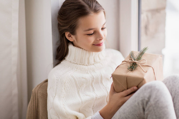 girl with christmas gift sitting at home - Photo, Image