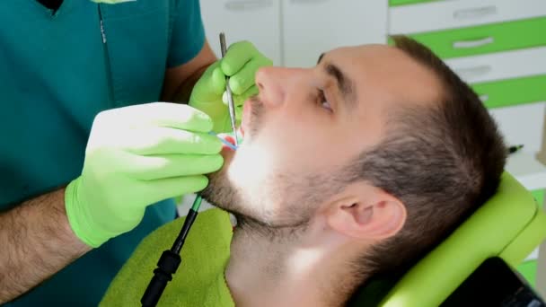 Detailní záběry, zubní ruce v zelené rukavice, upevnění zubů pacienta mužského pohlaví - Záběry, video