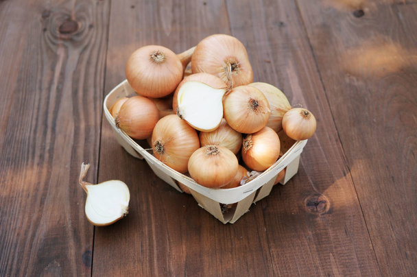 Zwiebeln auf einem Holztisch im Korb - Foto, Bild