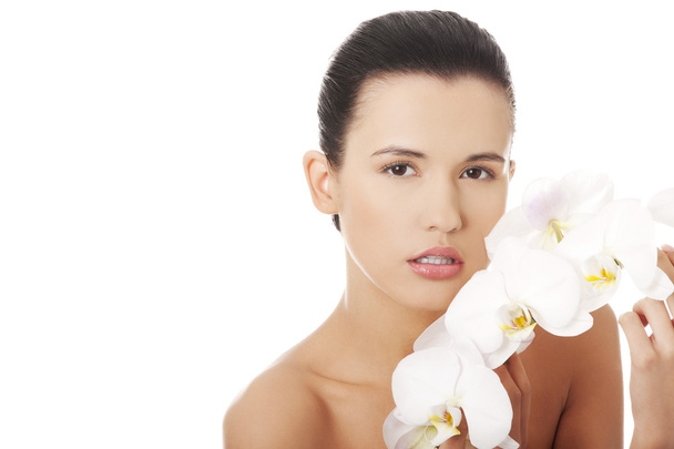 Beautiful young woman with orchid flower - Foto, afbeelding