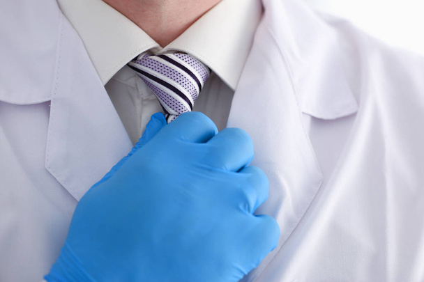 Um médico masculino em um vestido de vestir e camisa ajusta sua gravata
 - Foto, Imagem