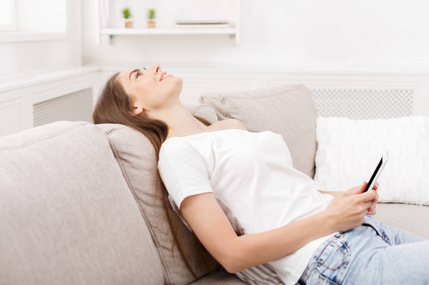 junge Frau mit Smartphone zu Hause auf der Couch. dunkelhaarige Mädchen in lässigen SMS online - Foto, Bild