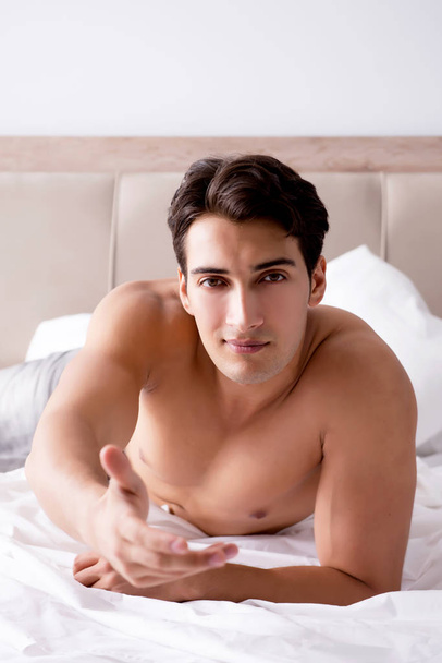 Young handsome shirtless guy showing nude torso sexy on bed at h - Foto, Bild