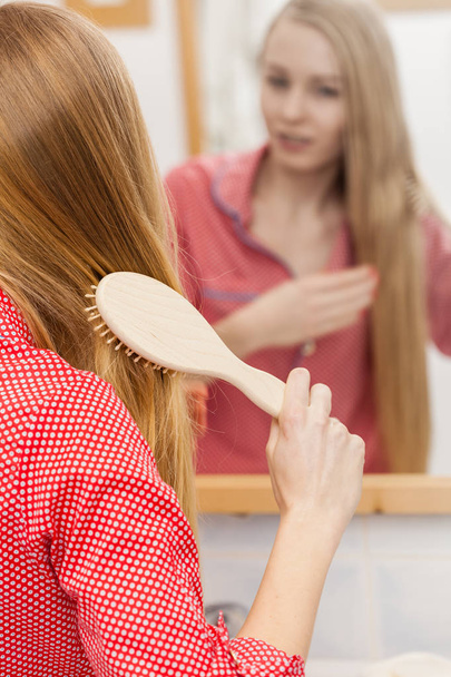 Woman brushing her long hair in bathroom - Φωτογραφία, εικόνα