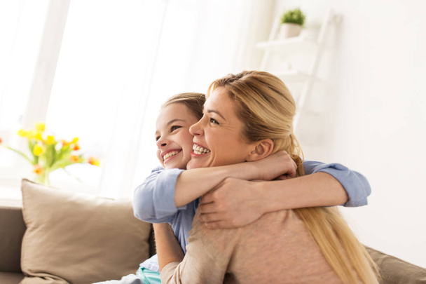 happy smiling family hugging on sofa at home - Zdjęcie, obraz