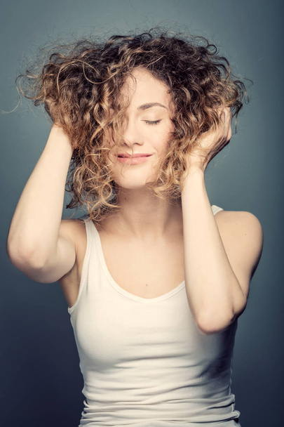 mulher segurando seu cabelo encaracolado para cima
 - Foto, Imagem