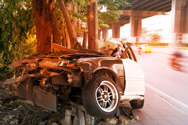 Wypadek samochodowy w Azji krytyczny, samochód rozbija się o drzewo i biegun elektryczny na chodniku. Katastrofa samochodowa w Azji z efektem świetlnym na tle. - Zdjęcie, obraz