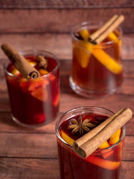 Glass Cup of red wine mulled wine on a wooden background with cinnamon spices and orange. Selective focus - Foto, Imagen
