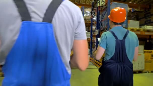 Férfi raktári alkalmazottak elsétálnak a több raktár folyosókon. - Felvétel, videó