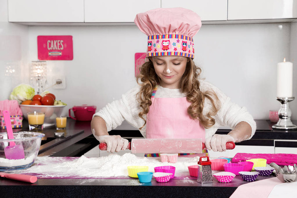 Hermosa niña divertida hija en delantales cocina cocina en las galletas de cocina y pasta fideos y pasteles
 - Foto, Imagen