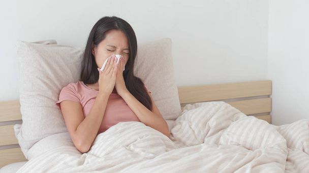 Woman sneezing on bed  - Photo, Image
