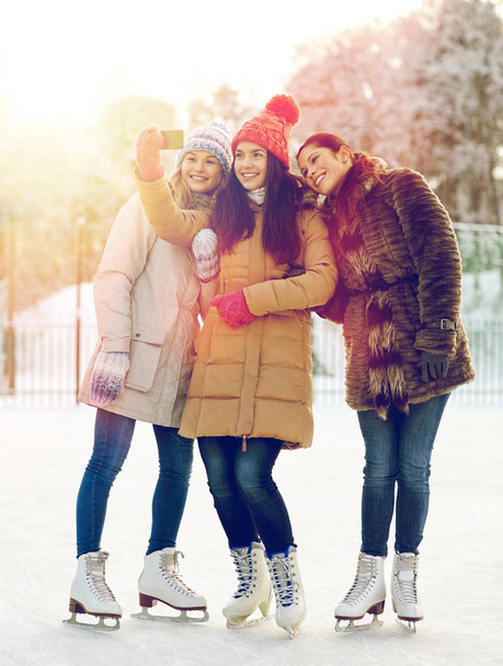 happy young women with smartphone on skating rink - Fotoğraf, Görsel