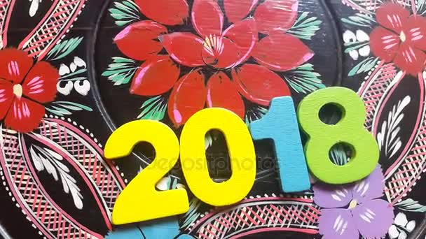 Die bunte Zahl 2018 dreht sich um eine runde Holzscheibe mit aufgemaltem Blumenschmuck - Filmmaterial, Video