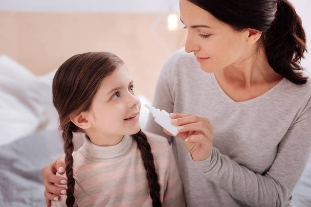 Loving woman giving nasal drops to a smiling child - Foto, Bild