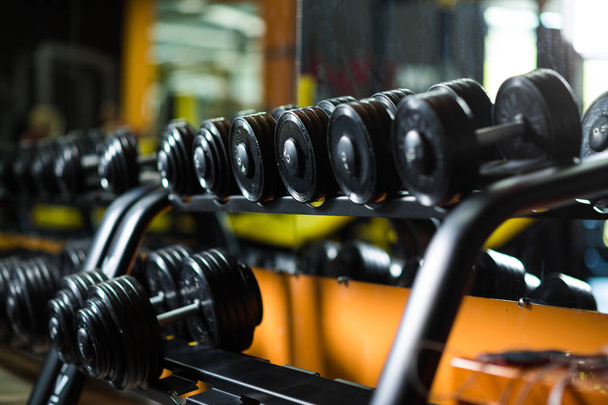 Iron dumbbells, equipment for weight lifting, gym, weight training, workouts, routines, increasing strength and size of muscles on a dark blurred background. - Foto, Imagem