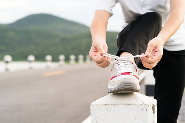 Mujer atando los cordones de sus zapatos antes de empezar a correr
 - Foto, imagen