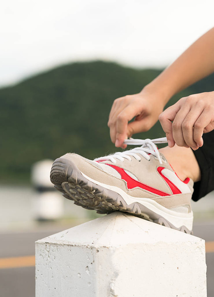 Mujer atando los cordones de sus zapatos antes de empezar a correr
 - Foto, Imagen