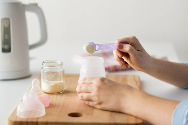 hands with bottle and scoop making formula milk - Foto, Imagem