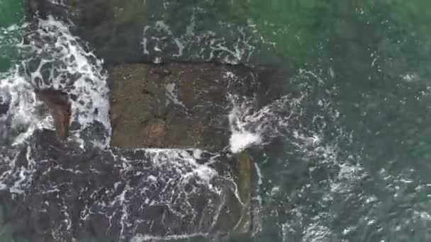 Εναέρια από τα κύματα του ωκεανού πλύσιμο σε ένα βράχο μαύρο βασάλτη - Πλάνα, βίντεο