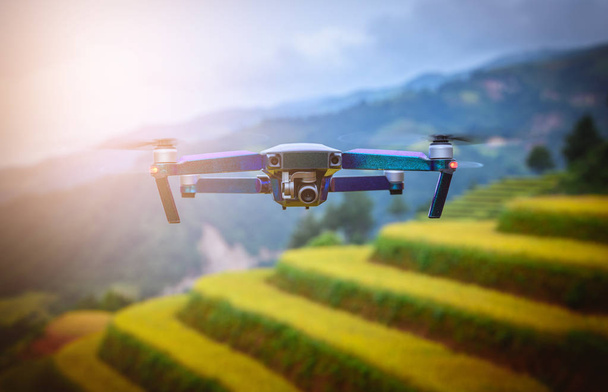 Drone RC moderno / Quadcopter con cámara volando en campos de arroz adosados al atardecer en Mu Cang Chai, YenBai, Vietnam
. - Foto, imagen