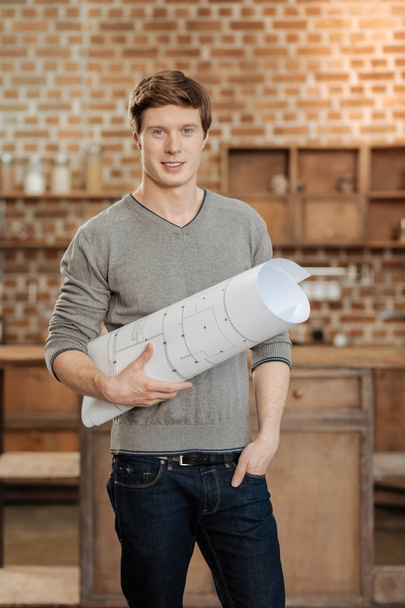 Charming man posing with a blueprint in studio - Photo, Image