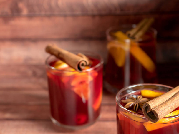 Glass Cup of red wine mulled wine on a wooden background with cinnamon spices and orange. Selective focus - Fotó, kép