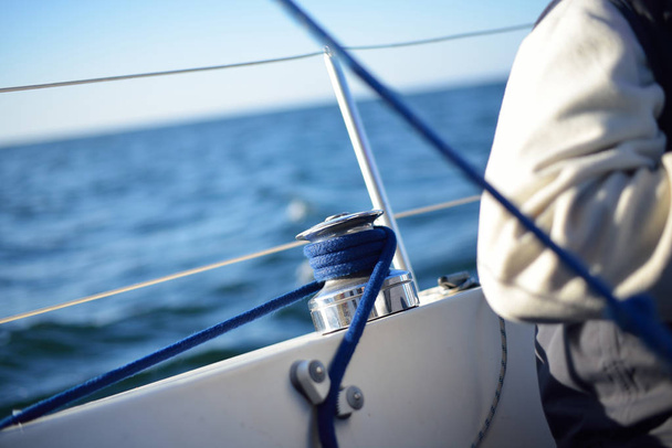 ein Mann sitzt neben einer Seilwinde auf einem Segelboot  - Foto, Bild