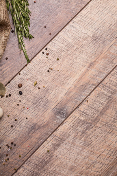 Primer plano de ramitas de romero verde fragante, diferentes condimentos aromáticos, mantel rústico, una mesa de madera clara sobre un fondo claro de madera
. - Foto, imagen
