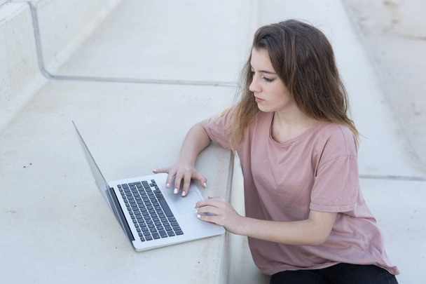 Adolescente sentada en una escalera con su portátil
. - Foto, imagen