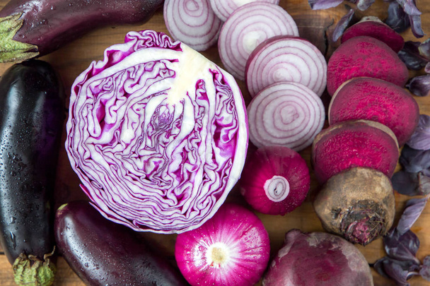 purple vegetables on wooden background - eggplant, beets, basil, onion, cabbage - Фото, изображение
