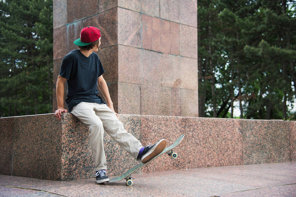 Schaatser zit met zijn rug en denkt dat naast het skateboard - Foto, afbeelding