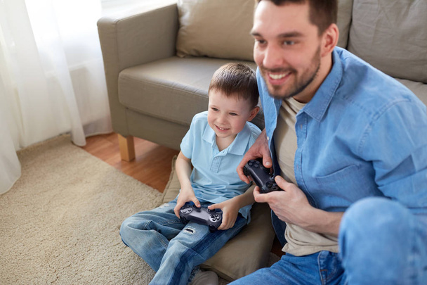 father and son playing video game at home - Foto, Imagen