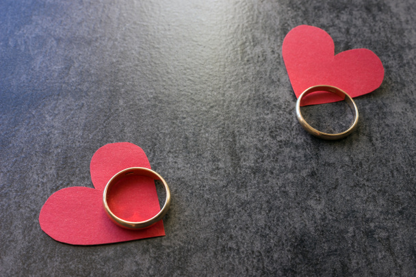 Anéis de casamento e coração vermelho. Fundo preto
.  - Foto, Imagem
