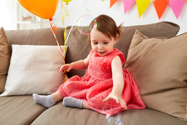 baby girl with soap bubbles on birthday party - Foto, afbeelding
