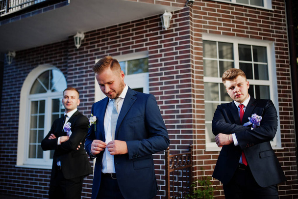 Handsome groom in his wedding tuxedo posing with groomsmen or be - Foto, imagen
