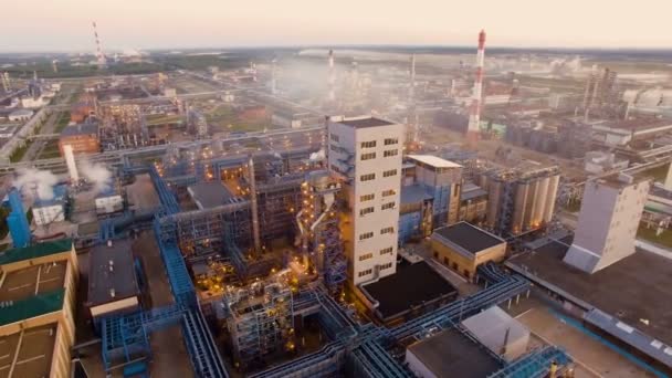 A huge oil refinery with metal structures, pipes and distillation of the complex with burning lights at dusk. Aerial view - Footage, Video