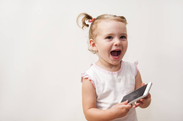 Bambina che gioca con un telefono cellulare
 - Foto, immagini
