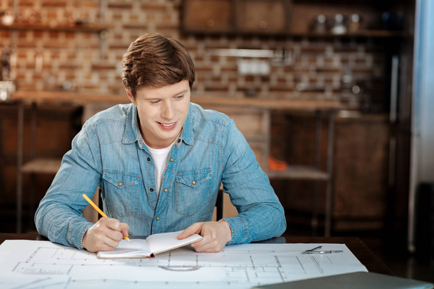 Cheerful young engineer doing calculations for his project - Фото, зображення