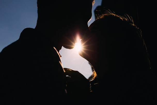 Kaksi rakastunutta suutelee aurinko paistaa huulien välissä.
.  - Valokuva, kuva