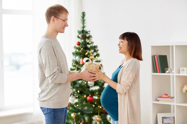 husband giving christmas present to pregnant wife - Foto, Bild