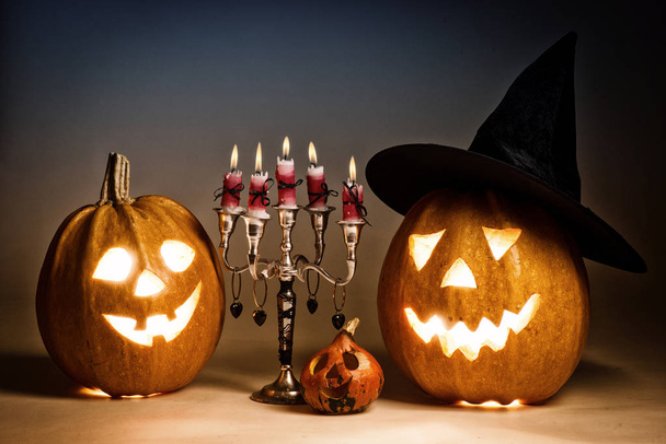 Halloween pumpkin with a candlestick, funny face face on a blue background. - 写真・画像