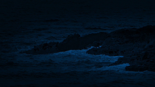 Océano olas rompiendo en las rocas por la noche
 - Metraje, vídeo