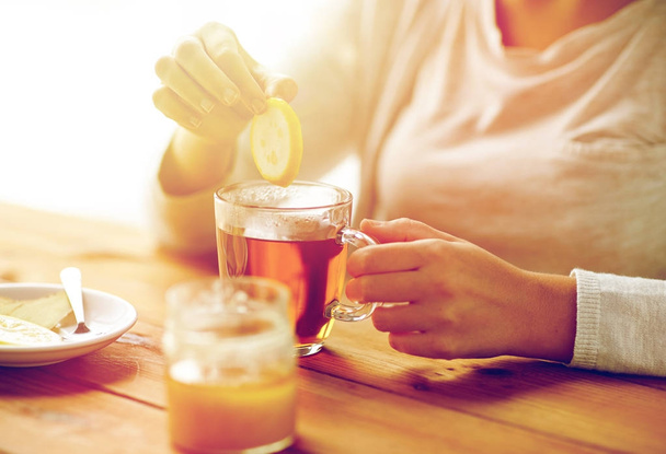 close up of ill woman drinking tea with lemon - 写真・画像