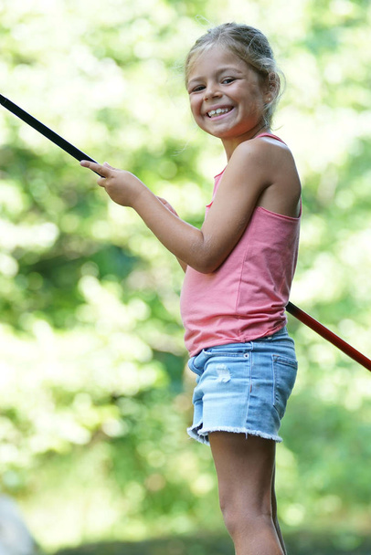 Smiling girl holding fishing line by river - Photo, Image