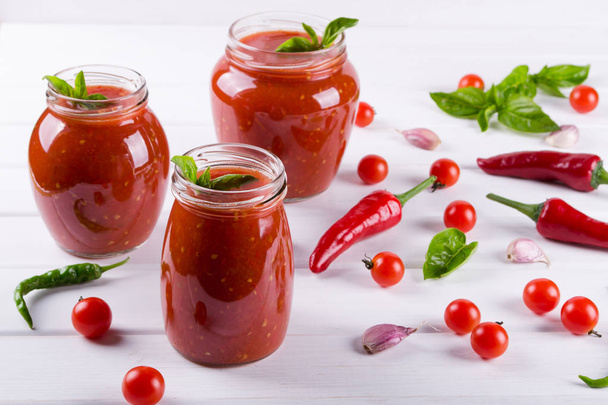 Salsa picante de tomate dulce con ajo, pimienta y hierbas en frascos de vidrio
. - Foto, imagen