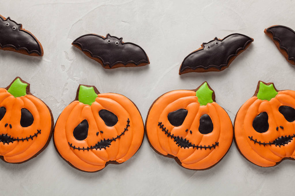 Zelfgemaakte gember koekjes in de vorm van pompoenen en vleermuizen op Halloween. Op de lichtere concrete achtergrond. Bovenaanzicht - Foto, afbeelding