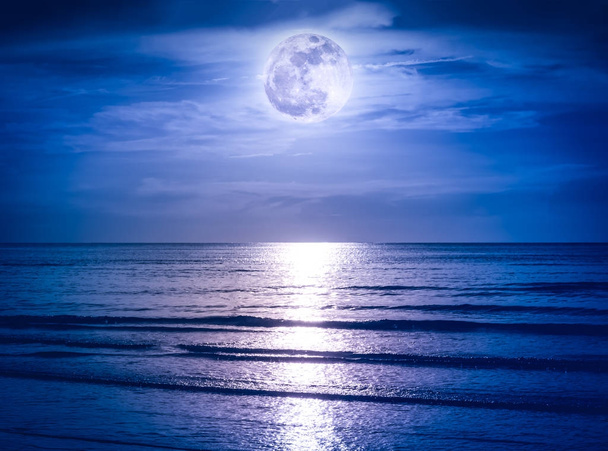 Céu colorido com nuvem escura e lua cheia brilhante sobre a paisagem marinha
. - Foto, Imagem