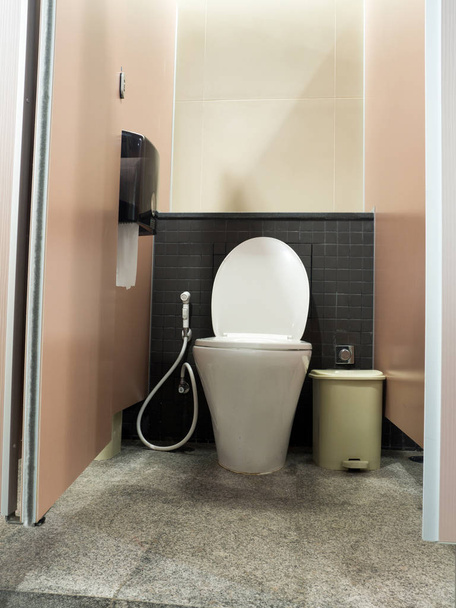 toilet door opening and white flush toilet with a trash cans and box of toilet paper. - Photo, Image